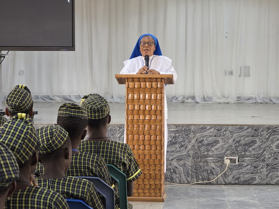 Sr. Chidebelu Nwigwe presenting an Award of Excellence to three students