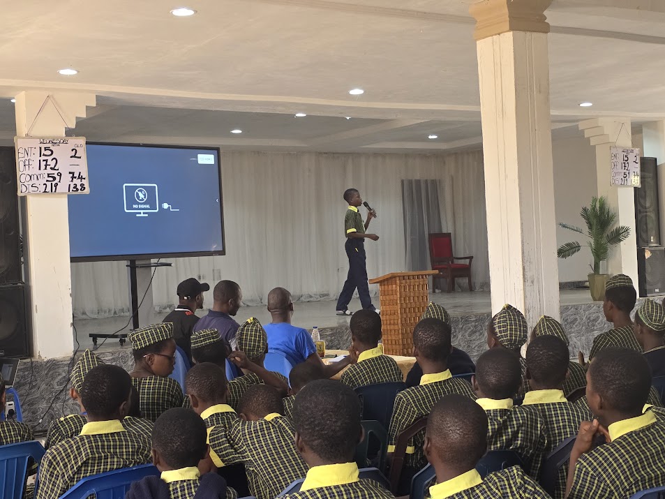 A student addresses his peers from the podium during a URIECEF school assembly